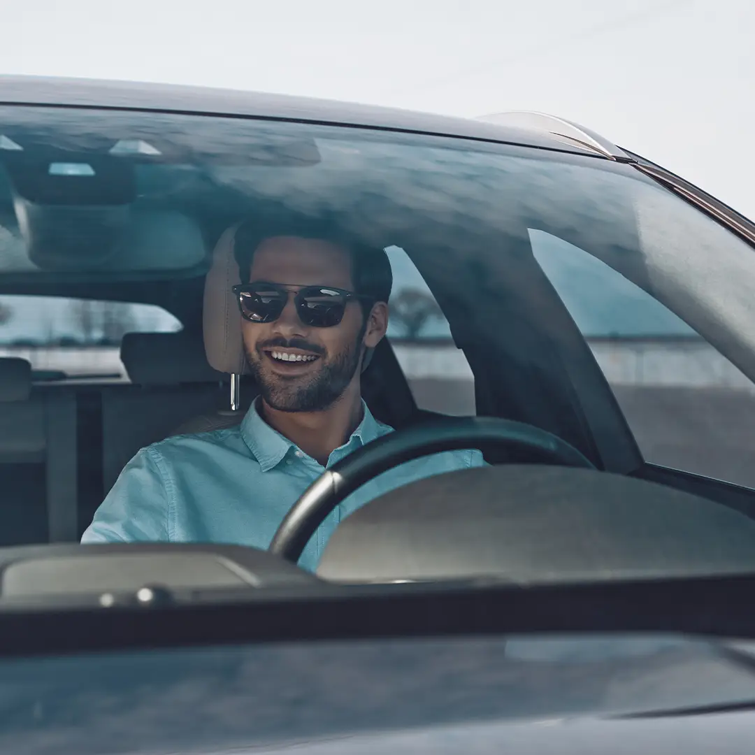 Chauffeur VTC souriant au volant, service client soigné